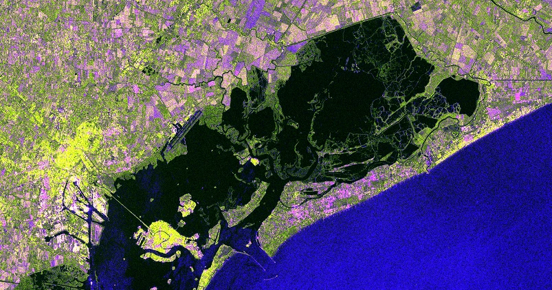 Satellitenbild vor der Flut mit gesunder Vegetation, klar abgegrenztem Lagunensystem und städtischen Bereichen.