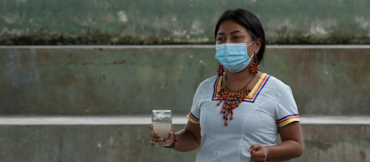 Verónica Grefa segurando um copo de água potável contaminada